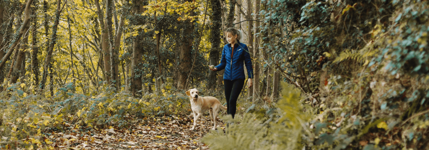 Woman playing fetch with her dog in the woods